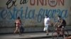 Residentes de La Habana pasan frente a un cartel con propaganda del régimen durante la pandemia de coronavirus, el 13 de abril del 2020.