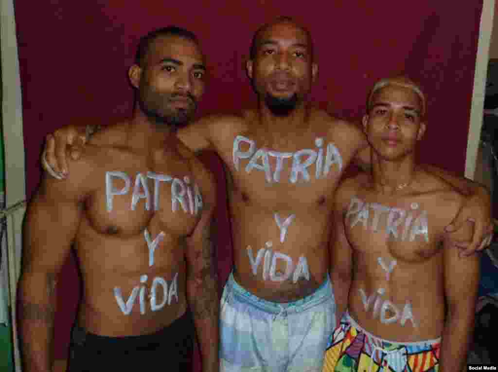 El activista Osmani Pardo Guerra junto a su hermano y su primo con el título de la canción "Patria y Vida" escrito en el cuerpo.