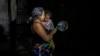 Una madre con su hija en brazos protesta golpeando una cazuela en medio del apagón general, en La Habana, el domingo 20 de octubre de 2024. (Foto AP/Ramon Espinosa)
