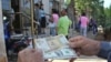 Un hombre muestra un peso convertible cubano y un dólar estadounidense frente a una oficina de la Western Union en La Habana.